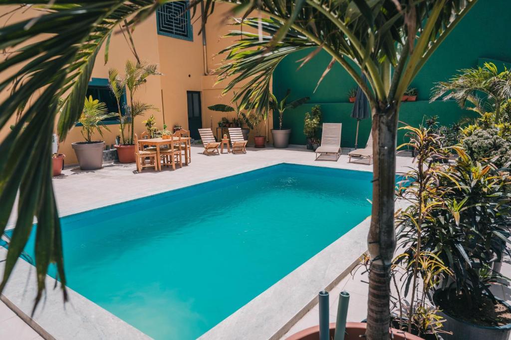 a swimming pool with palm trees and a table and chairs at Casa Jardim di Sol in Praia