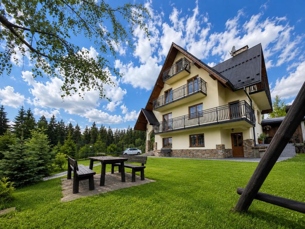 a house with a picnic table and benches in the yard at U Celiny - Widok na Tatry - Region Białki Tatrzańskiej in Rzepiska