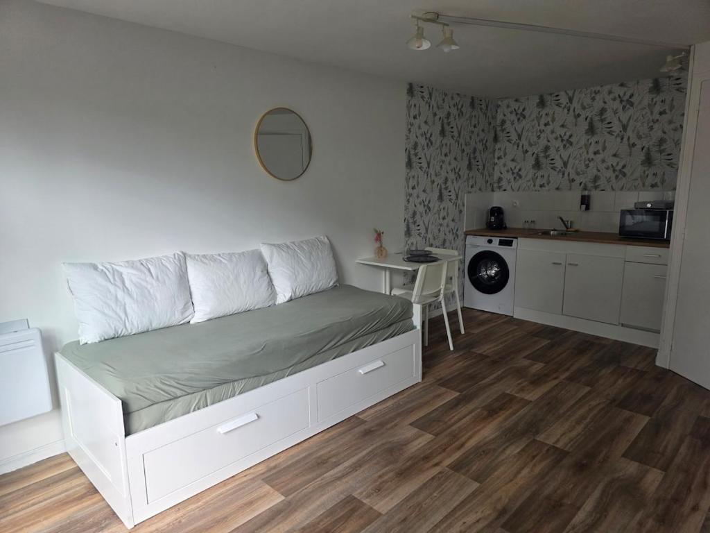 a bedroom with a white bed and a kitchen at Côté Jardin in Bolbec