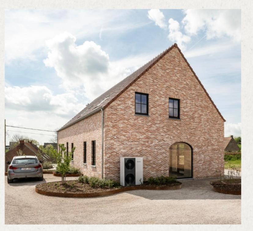 a brick house with a car parked in a driveway at Villa Cdv in Ellezelles