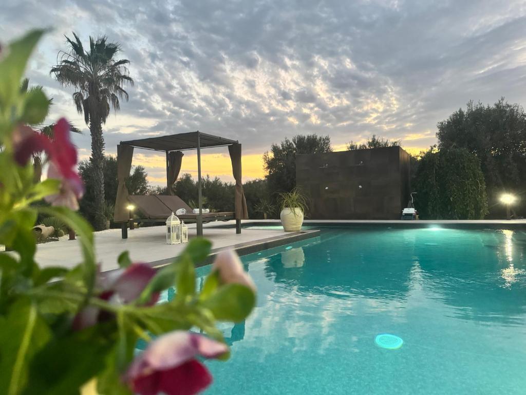 a swimming pool with a gazebo and a palm tree at Villa Badessa in Noto
