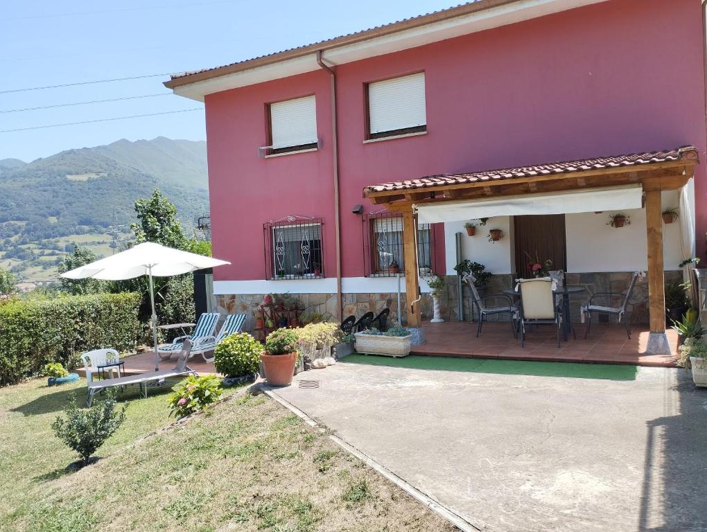 a pink house with chairs and an umbrella at Ca Blanca in Sorribas