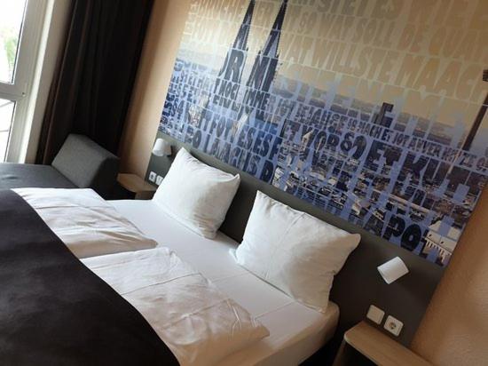 ein Schlafzimmer mit einem weißen Bett und einem Poster an der Wand in der Unterkunft FlatDeCologne - Sommer in der Stadt- City Apartment Nähe DOM in Köln