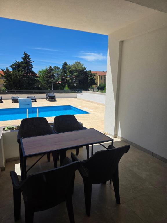 a dining room with a table and chairs and a pool at ANTODO Batista in Novalja