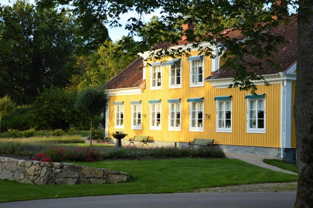 a yellow house with a bench in front of it at STF Grimsnäs Herrgård in Ljuder