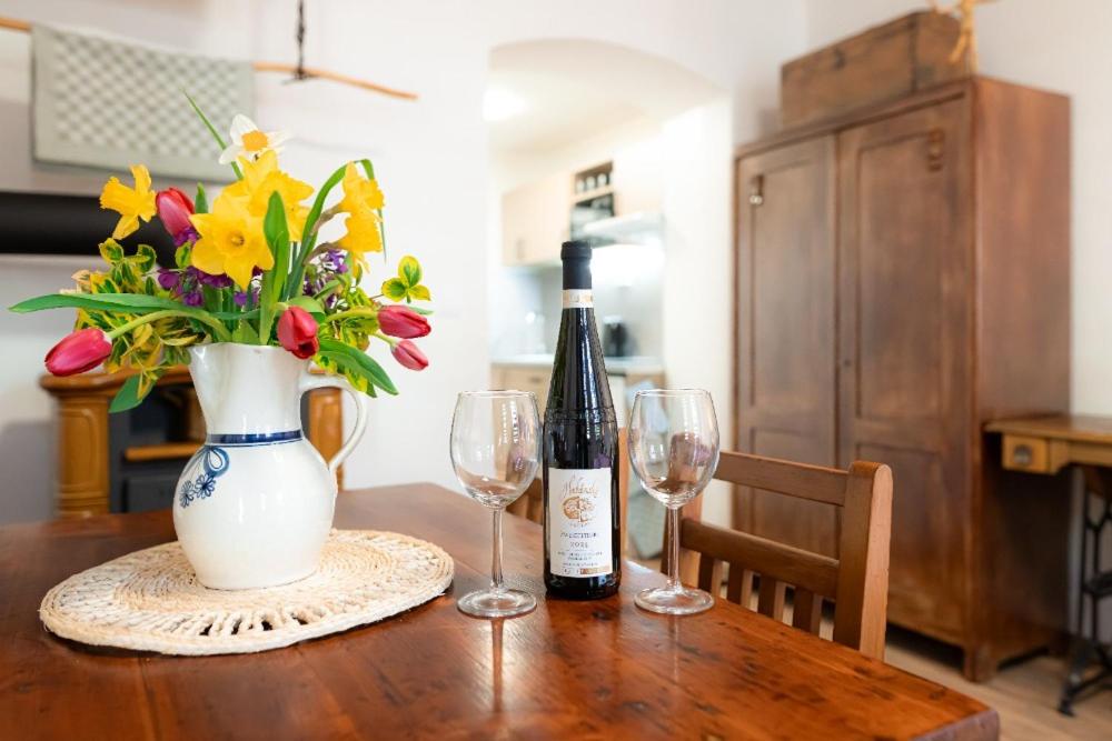 a table with a bottle of wine and two glasses at Apartmán Mafin in Jáchymov