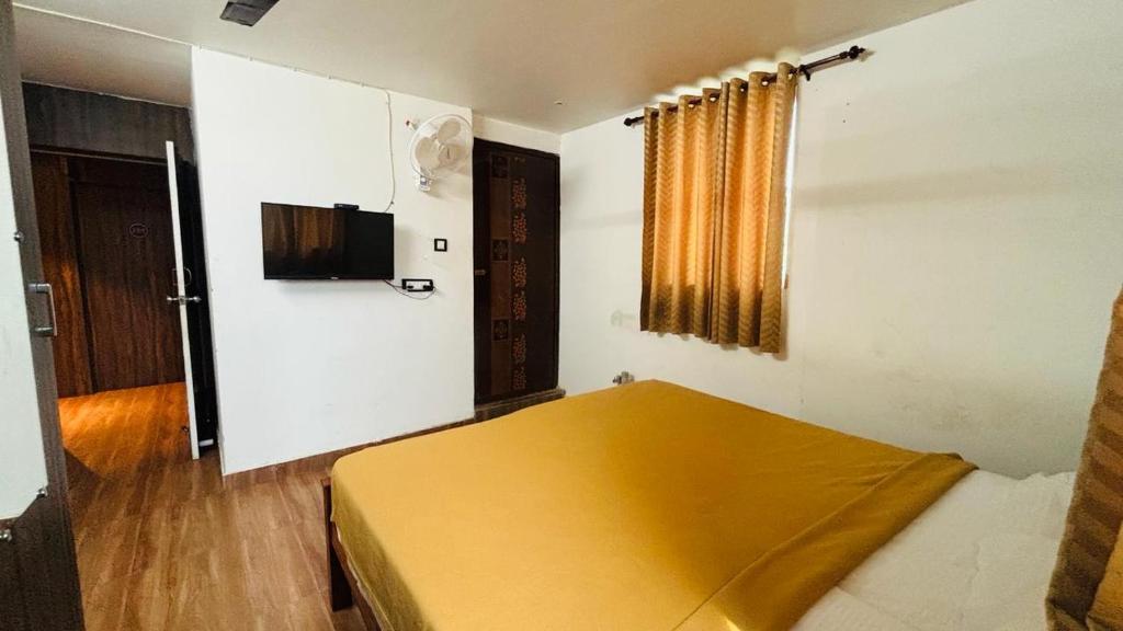 a room with a bed with a yellow cover on it at Hotel Royal Nest Inn in Coimbatore