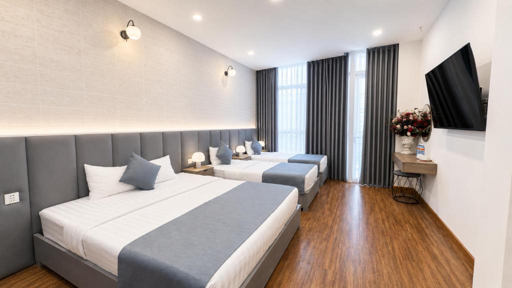 a hotel room with two beds and a flat screen tv at Beauty House in Ho Chi Minh City