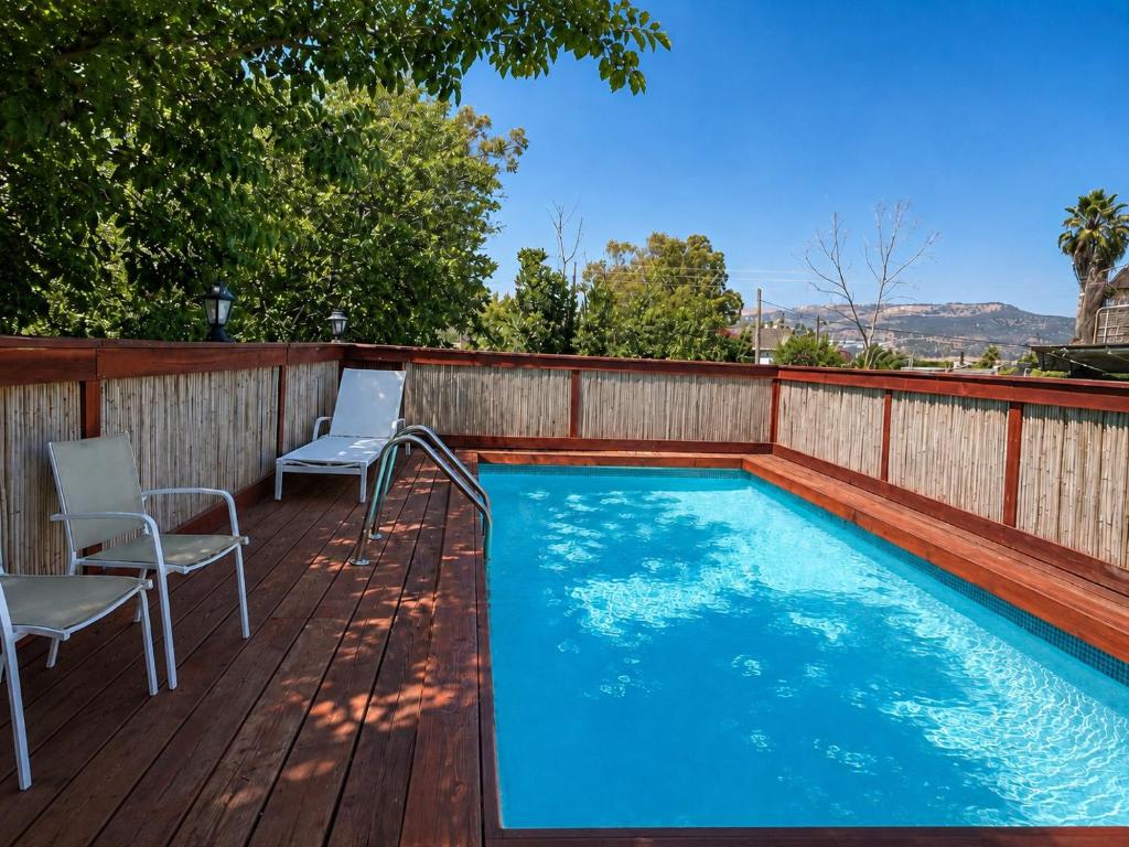 a swimming pool on a wooden deck with two chairs at פינה במעיין in Mishmār Hāyardin
