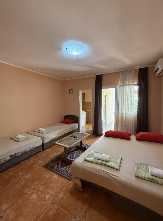 a room with three beds and a table in it at Maja Apartmani in Sutomore