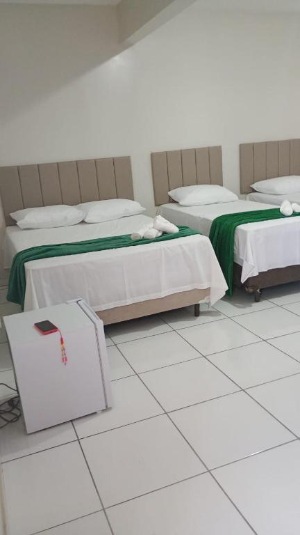 two beds in a room with white tile floors at Hotel Paulista Sobradinho BA in Sobradinho - Bahia