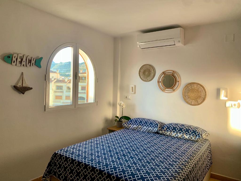 a bedroom with a bed with a blue comforter and a window at Bella Javea in Jávea