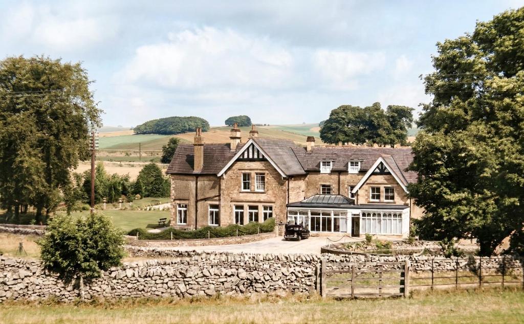 an old stone house with a stone wall at New Inns in Alstonfield