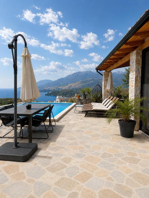 a patio with a table and an umbrella next to a pool at Terracotta Villa in Himare