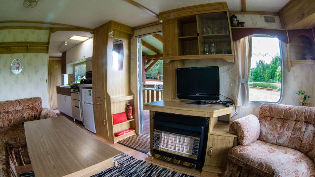 a living room with a tv and a fireplace in an rv at Domek Samanta in Grzybina