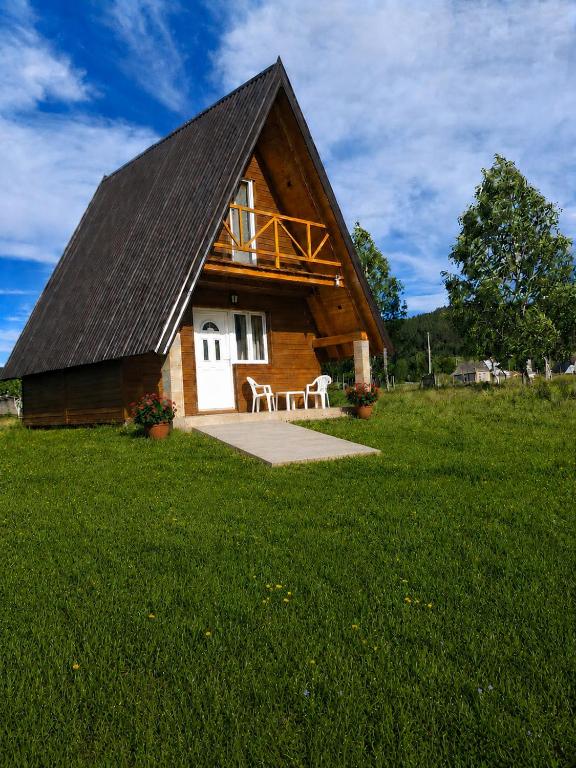 a cabin with a gambrel roof on a grass field at Durmitor Holiday in Žabljak