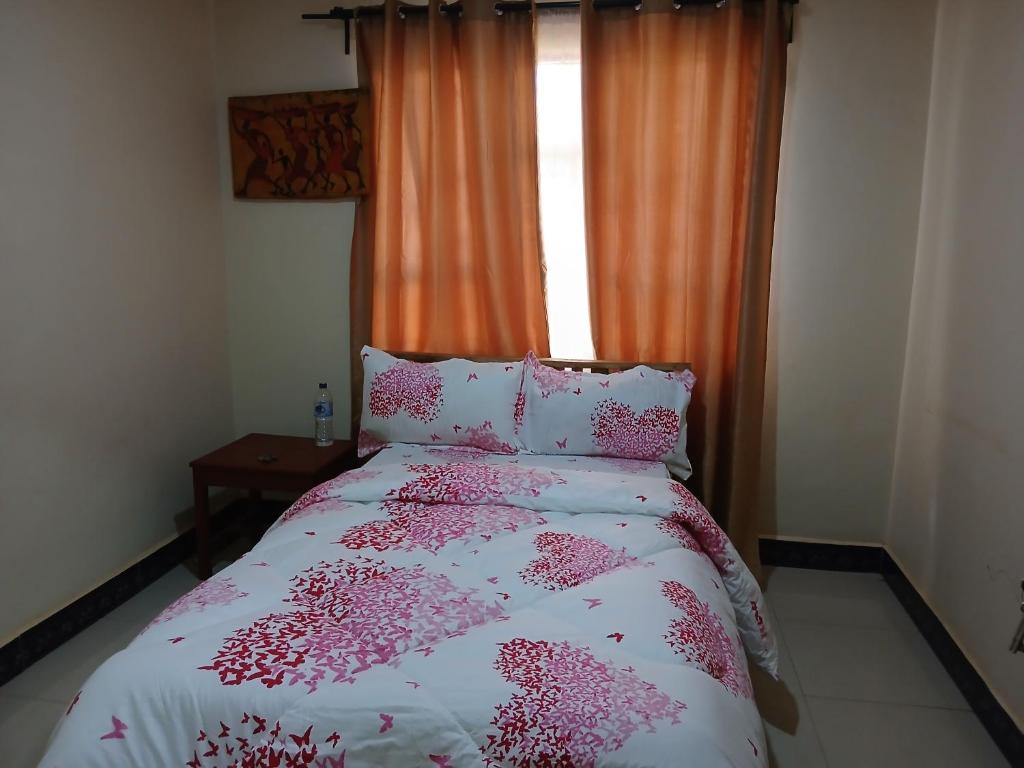 a bedroom with a bed with pink flowers on it at Friendly hostel in Arusha