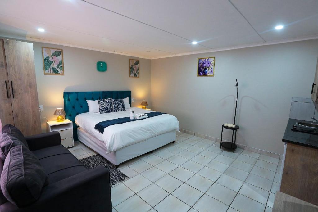 a bedroom with a bed and a couch at Ferry Palms Guest Lodge in Arcadia