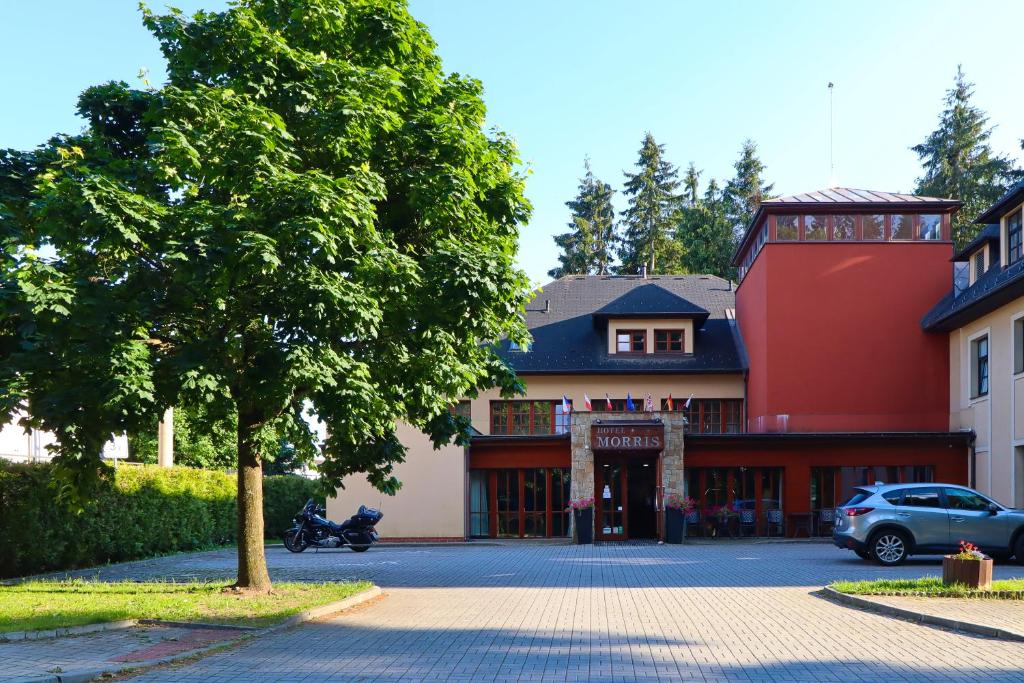 a red building with a tree in front of it at Wellness Golf Hotel Morris in Mariánské Lázně