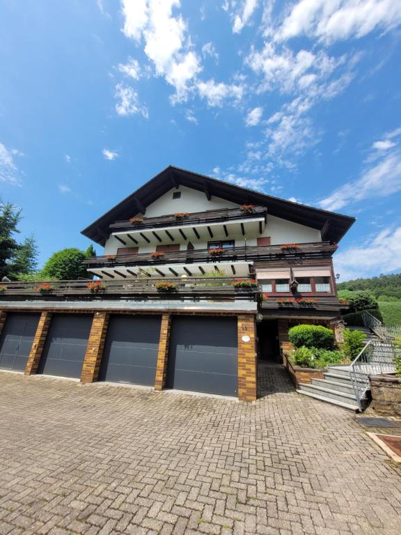 a house with two garage doors on a brick driveway at Pension Schöne Aussicht in Witzenhausen