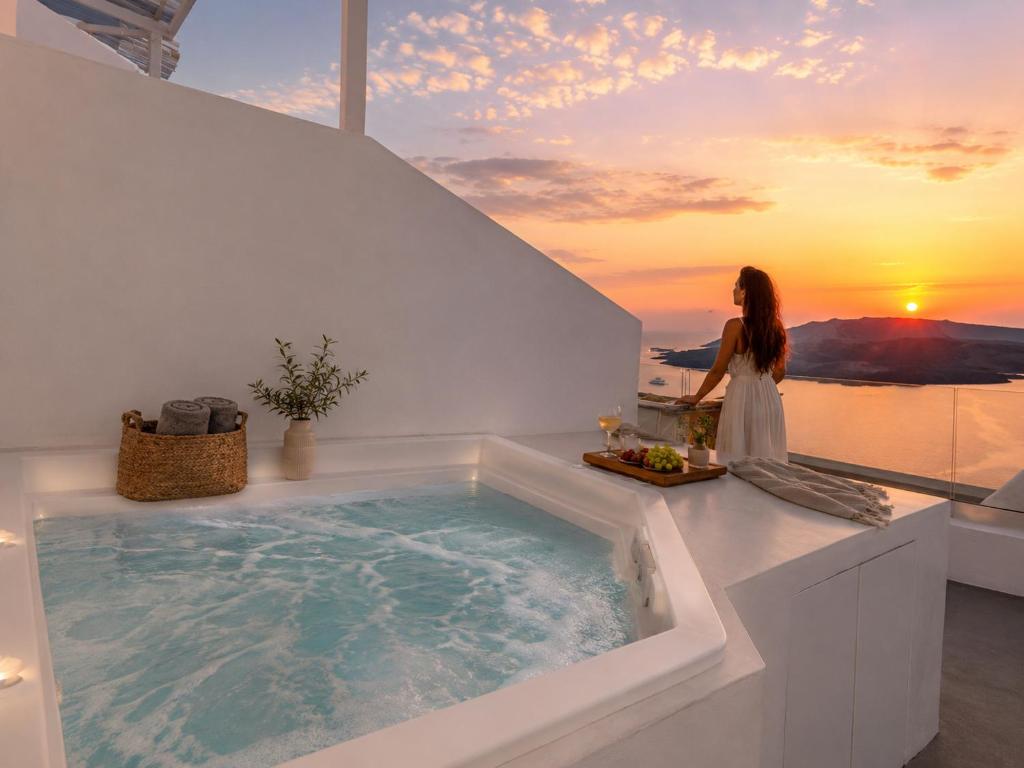 a woman standing in front of a bath tub with the sunset at Cliff Caldera Modern Suites -Volcano, Sunset & Caldera View in Fira