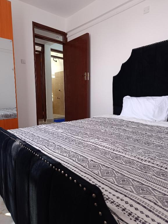 a bedroom with a large bed with a black headboard at BR Homes 2 Bedroom in Bungoma