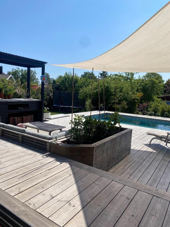 a wooden deck with a patio umbrella over a pool at Enplansvilla med pool in Tyresö