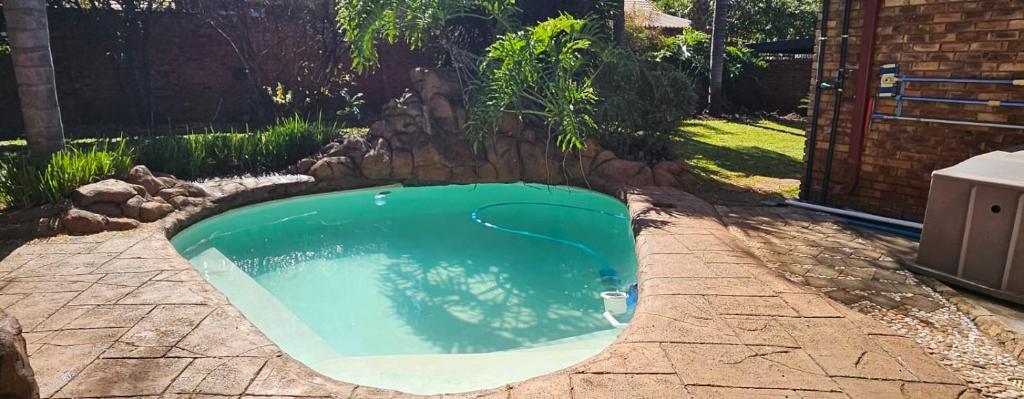 a small swimming pool with a rock wall around it at Oblique Boutique House in Centurion
