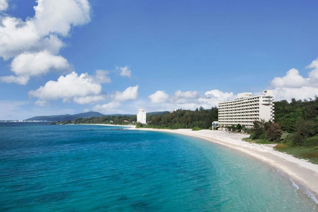 a view of a beach with a building and the ocean at Courtyard by Marriott Okinawa Resort in Nago