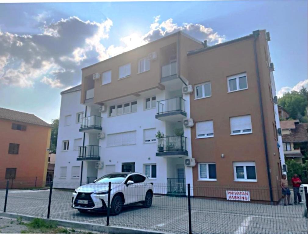 a white car parked in front of a building at Apartman Jakovljević in Gornja Toplica