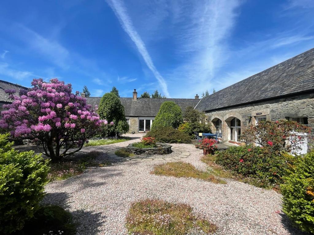 a garden in front of a house with a flowering tree at The Steading at Barmore in Tarbert