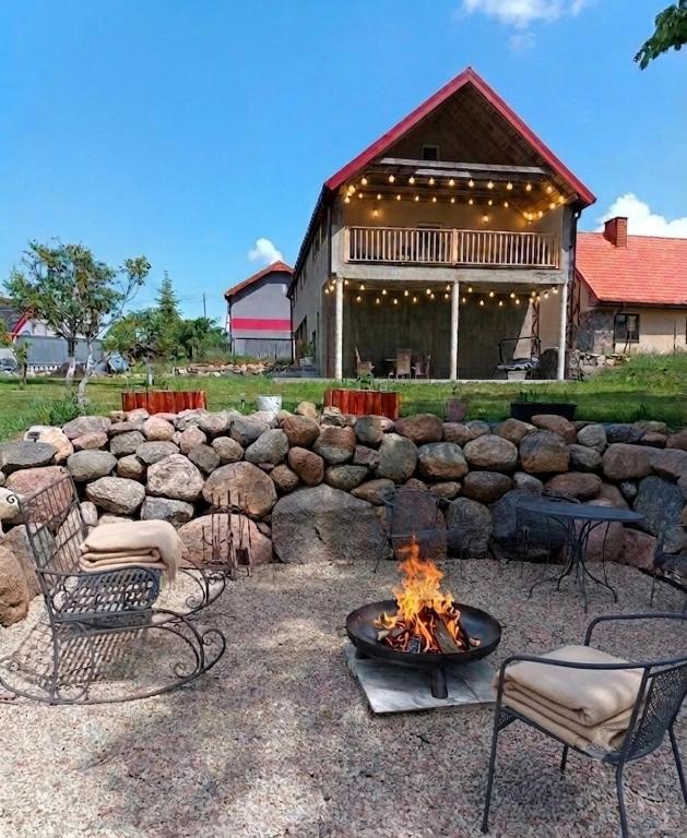 a fire pit in front of a stone wall at Łapacz Mazurskich Chwil in Orzysz