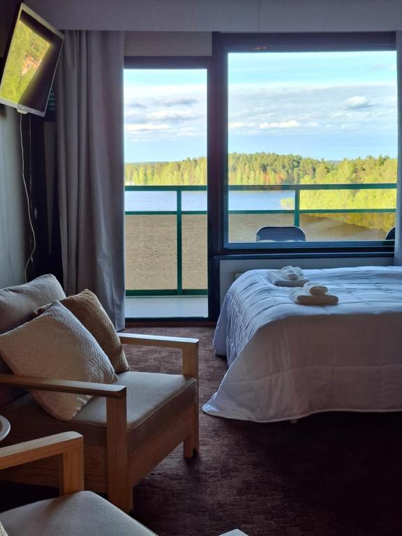 a hotel room with a bed and a large window at Huone upealla järvimaisemalla in Ikaalinen