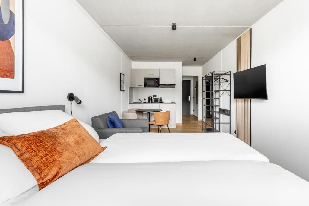 a bedroom with a white bed and a living room at Global Living Passau Ludwigplatz in Passau