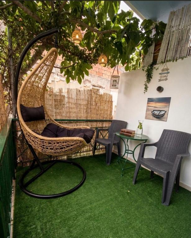 a hammock on a balcony with a table and chairs at FLISVOs 70 m από την θάλασσα in Erateini