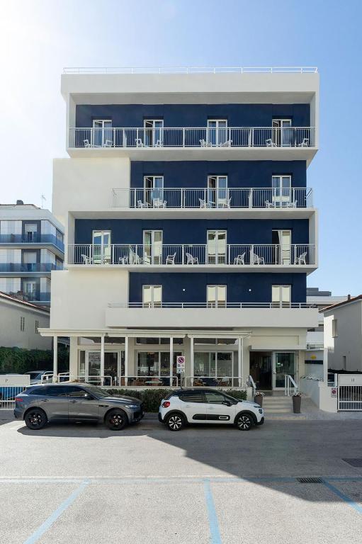 two cars parked in a parking lot in front of a building at Hotel Paradiso in Senigallia