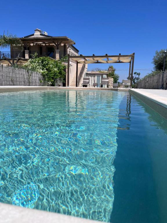 a swimming pool with blue water in front of a house at Bàcula Nzícula Marzamemi in Marzamemi