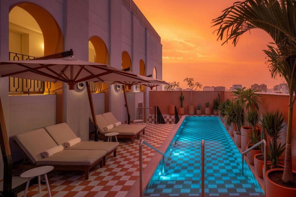 a swimming pool with chairs and an umbrella on a building at Humano, Lima, a Tribute Portfolio Hotel in Lima