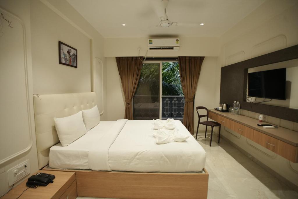 a bedroom with a large white bed and a desk at The Grand Leela Resort in Khopoli