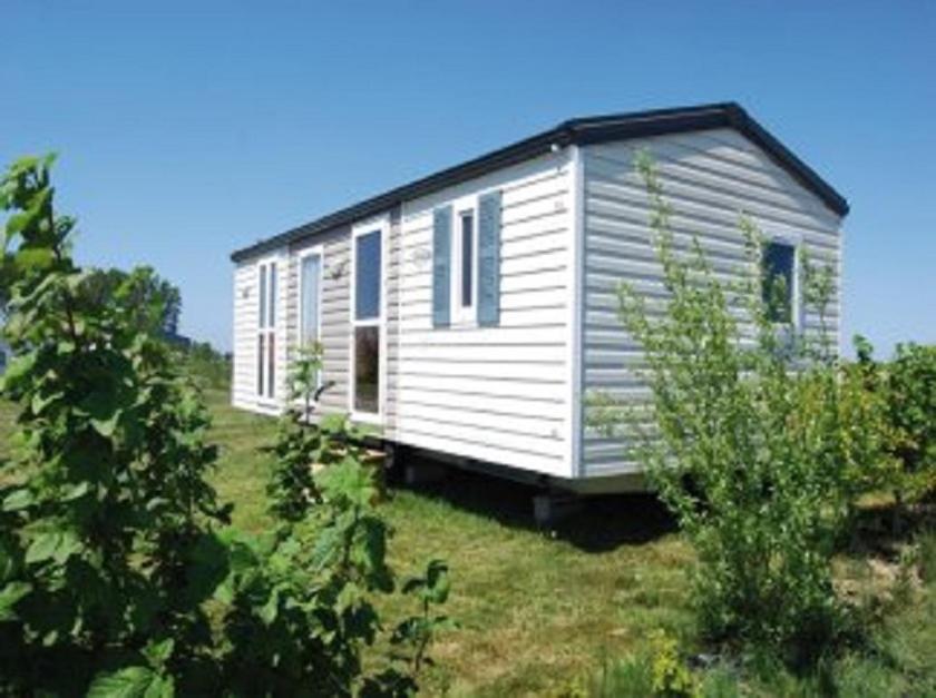 una casita blanca en una colina con árboles en camping de la mottelette en Forest-Montiers