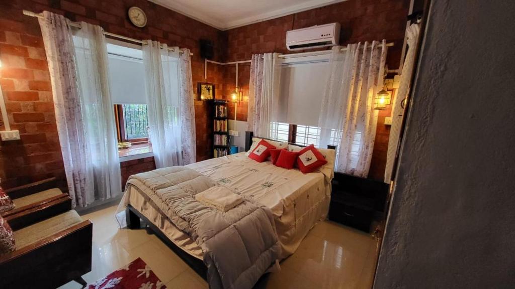 a bedroom with a bed with red pillows on it at The Brick Nest in Perumpāvūr