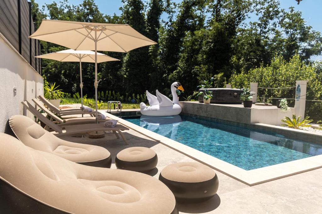a swimming pool with chairs and a swan float at Apartments Kuc in Tivat