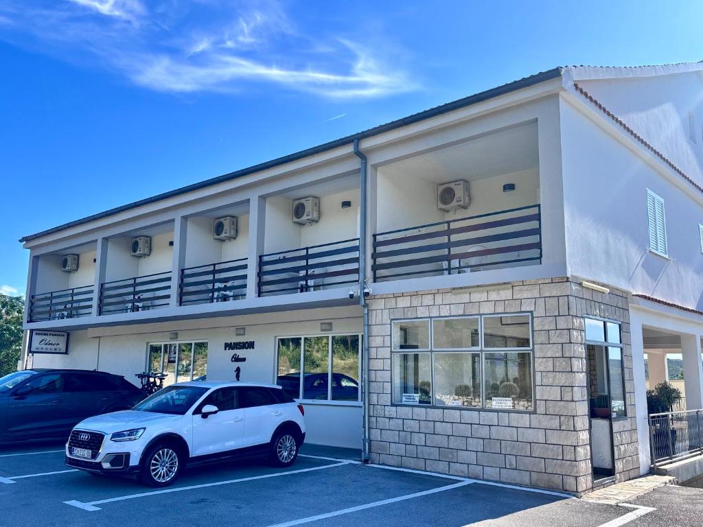a white car parked in front of a building at Rooms & Pansion Odmor in Rovanjska