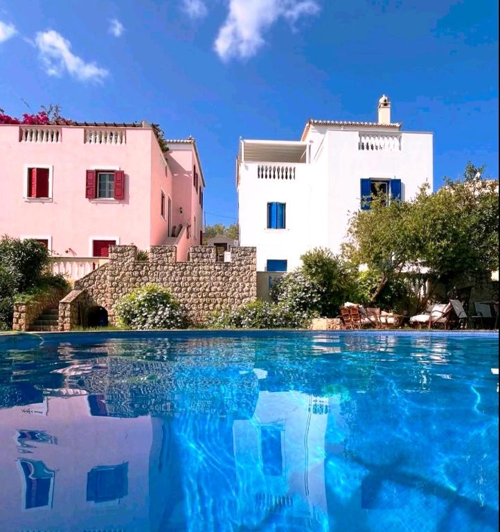 a swimming pool in front of two buildings at Castelli Retreat in Spetses