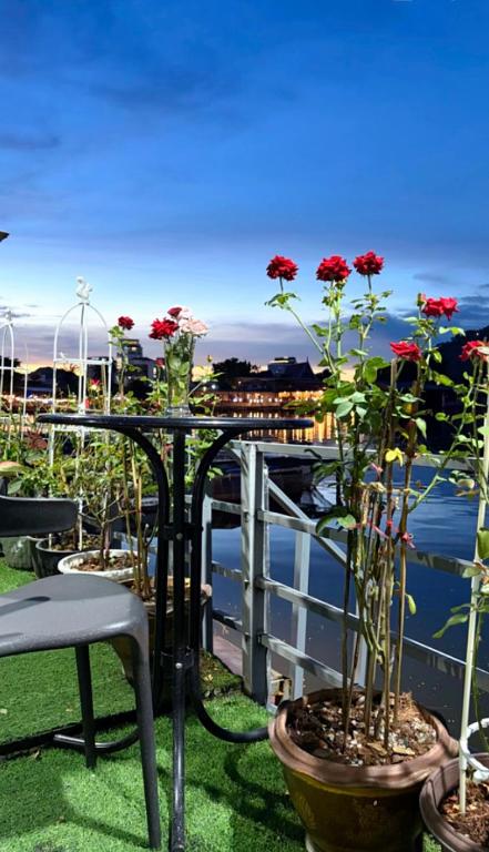 a table with red flowers on a balcony at Riverside Hostel Phuket in Phuket