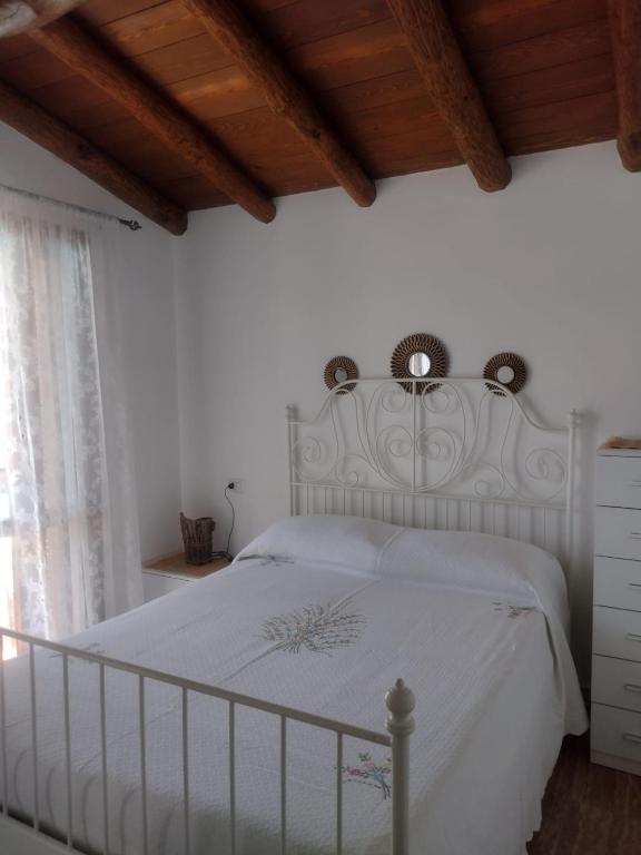 a white bed in a bedroom with a wooden ceiling at KaraA'mare in San Teodoro