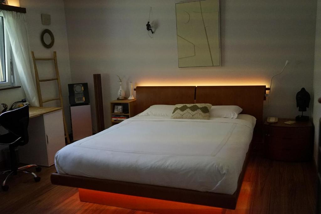 a bedroom with a large white bed with a wooden headboard at The Comfy Apartment in Ponte Capriasca