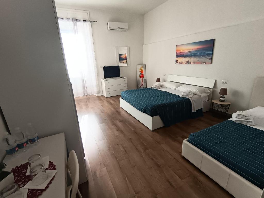 a bedroom with two beds and a television in it at Manì Rooms Villanova in Cagliari