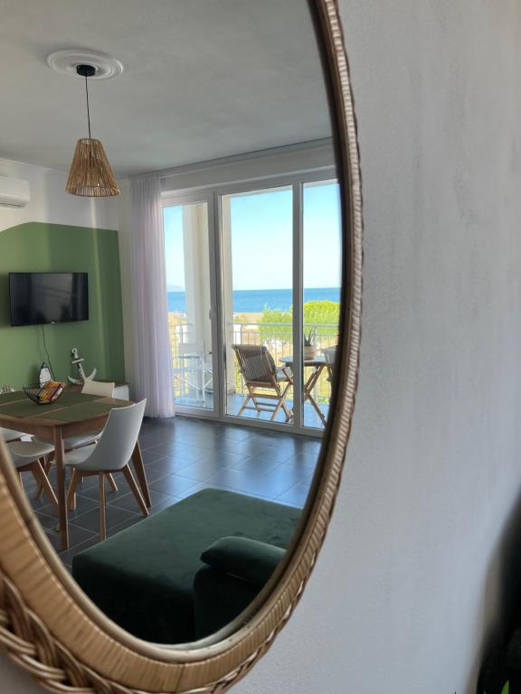 a mirror reflecting a living room with a table and a dining room at Andrra Apartment - Talea Coast in Lezhë