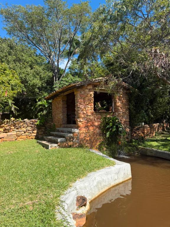 a brick building next to a body of water at Pousada e Camping Sá Zabé in Rio de Contas